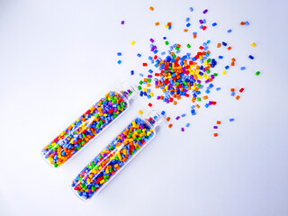 Colorful polymer masterbatch gradation, colorful pigment resin pellets in glass tubes poured on a white background, suitable as a product catalog design for industrial plastic manufacturing companies