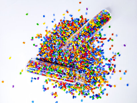 Colorful polymer masterbatch gradation, colorful pigment resin pellets in glass tubes poured on a white background, suitable as a product catalog design for industrial plastic manufacturing companies