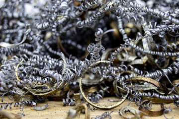 Close-up of industrial metal swarf/shavings, a curly gray byproduct from machining processes like turning and milling, highlighting texture for recycling.
