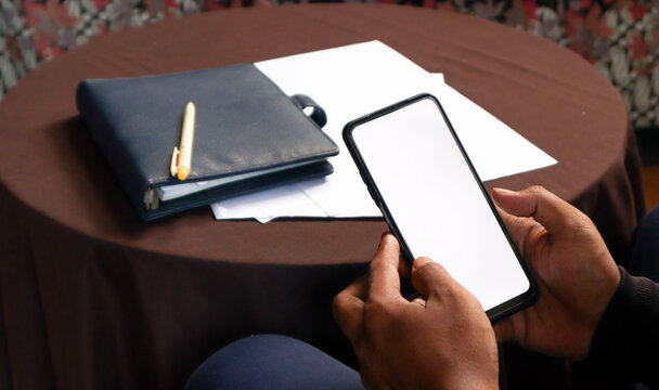 Close Up of Smartphone with white Screen Mock Up Display In Male Hands. Man Sitting In Home Browsing Internet , Watching Content, News, Financial Reports on Phone.  - Powered by Adobe