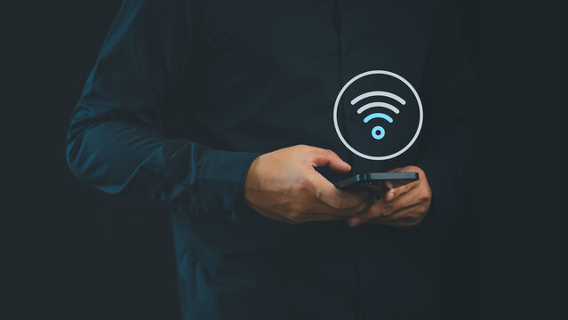 Person holding a smartphone with a Wi-Fi icon symbolizes wireless connectivity, mobile internet access, network communication, hotspot usage, and modern digital lifestyle in everyday technology.