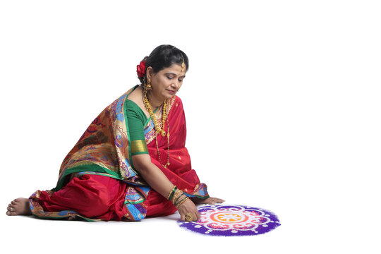 Portrait of Maharashtrian woman making a rangoli in navari saree. Isolated on white background.
