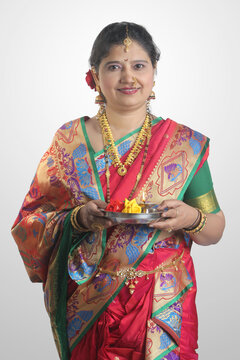 Beautiful Indian Maharashtrian woman in Red traditional ethnic nauvari saree holding a puja thali showing Indian culture, religion and fashion.
