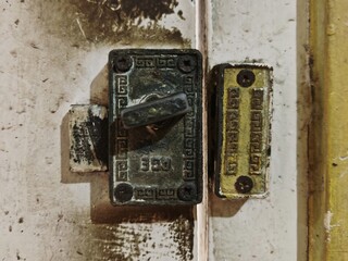 An old, weathered metal latch showing its age through rust and faded paint.