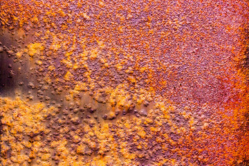 Metal surface with a thick layer of rust, exhibiting a predominantly purple hue with hints of orange and a rough texture