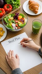 Woman creating a healthy meal plan with fresh salad, vegetables, and juice on a wooden table.