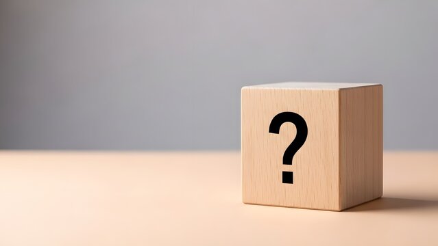 Wooden block with question mark symbol on tabletop against gray background
