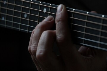 Close-up of hand pressing guitar strings on fretboard