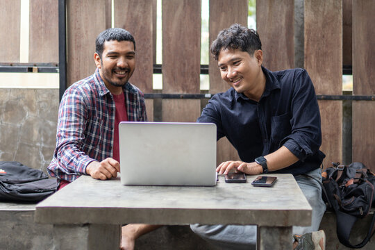 Two men working together in an outdoor cafe space