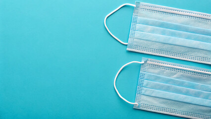 Two blue medical masks rest side by side on a vibrant blue surface, highlighting the importance of health precautions during a pandemic, promoting safety for individuals and communities.