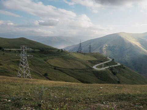 Scenic mountain road surrounded by mountains and high-voltage power transmission towers