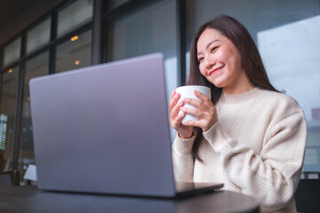 Fototapeta premium Portrait image of a woman working on laptop computer while drinking coffee in cafe