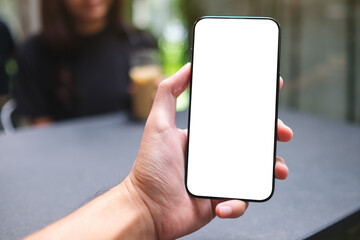 Mockup image of a man holding mobile phone with blank screen  with a blurred woman in background