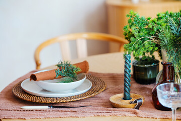 Table setting with green candle and pine greenery on rustic cloth