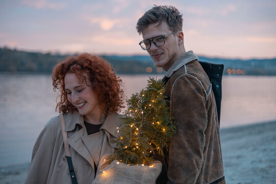Candid couple sunset portrait with fairy lights and beach backdrop in wintertime