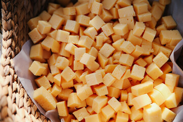 Yellow cheese cubes served as appetizers in a rustic wicker basket