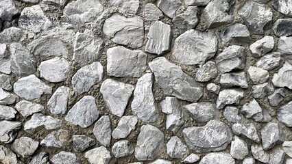 Textured gray stone wall composed of irregularly shaped rocks, showcasing natural patterns and variations, ideal for backgrounds or architectural design elements