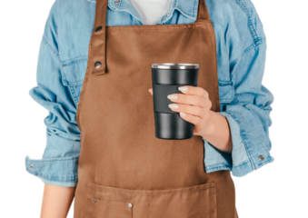 Person in a brown apron holding a black reusable thermal cup, isolated, coffee shop concepts, barista themes, take-away drinks, service industry advertising and eco-friendly lifestyle visuals
