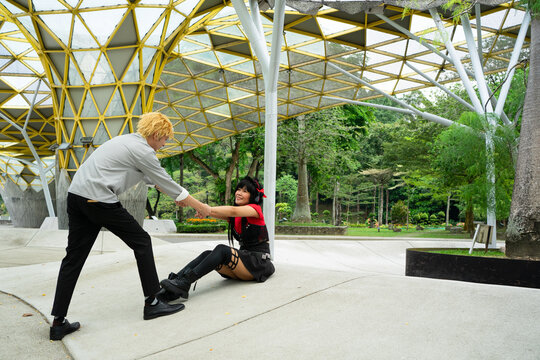 Cosplayers helping each other under modern structure in a park