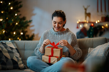 woman with present near Christmas tree indoors