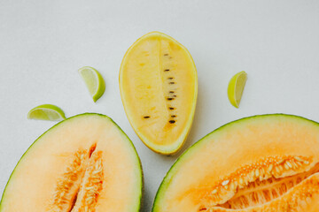Yellow watermelon halves with fresh lime wedges on a clean white background.