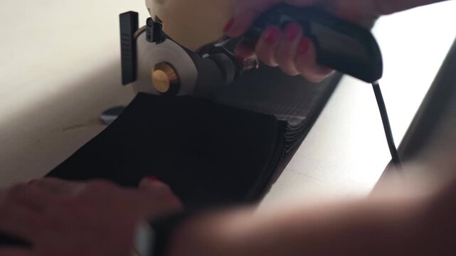 Rotary fabric cutter slicing stacked black technical material on work table