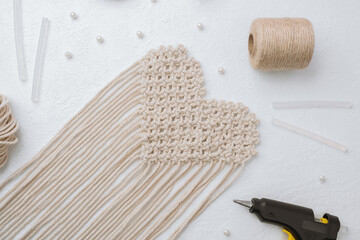 Heart macrame with glue gun and cord on white background