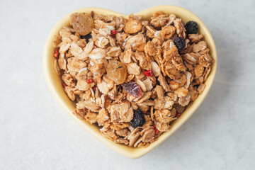 Heart shaped bowl with granola mix on light background