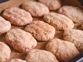 Close-up shot of raw breaded meat cutlets on a parchment paper on a baking tray ready to be cooked