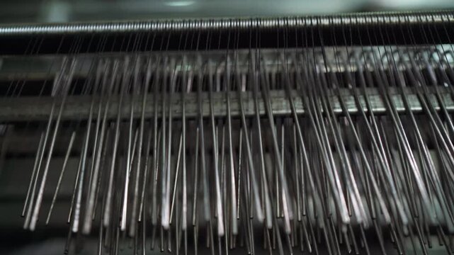 close-up row of metal needles sweeping across bed, rhythmic motion and glinting tips, high-speed alignment checks, factory inspector verifying spacing