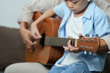Family Life: Father teaching son to play guitar at home