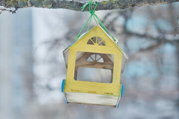 A yellow birdhouse on a tree branch