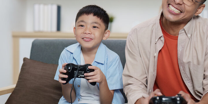 Family Life: Father and son playing video games together at home