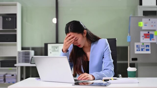 Frustrated young businesswoman working on a laptop computer sitting at his working place in office