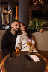 Romantic couple sitting close together in a cozy café with a cup of cappuccino on the table
