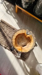 An aerial view shows freshly brewed coffee dripping into a glass dripper placed on a light brown towel, with morning sunlight casting beautiful shadows on the light-colored tile floor.