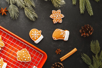 Christmas cookies shaped like mittens snowflakes and hats on tray with pine cones