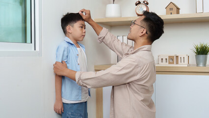 Family Life: Father measuring son's height at home
