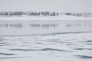 Winter landscape: ice and snow on the river in cloudy weather
