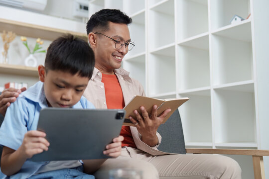 Family Life: Father and son enjoying digital reading together - Powered by Adobe