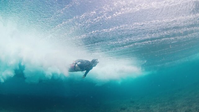 Surfer passes the wave in the ocean in the Maldives with surfing board.