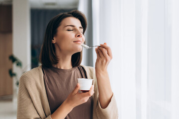 Smiling woman enjoying healthy yogurt for breakfast or snack