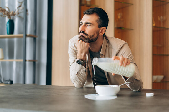 Distracted man spilling milk during breakfast at home
