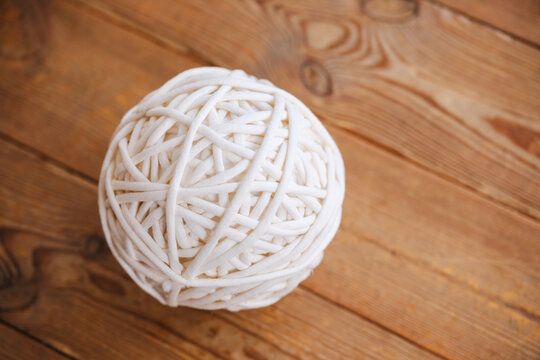 White yarn ball resting on rustic wooden planks background, close up overhead view.