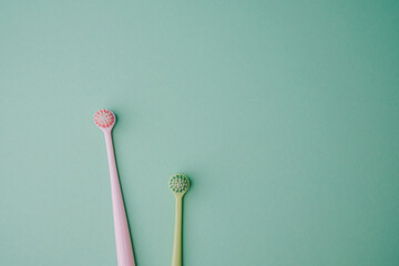 Two colorful toothbrushes laid out on a plain pastel background