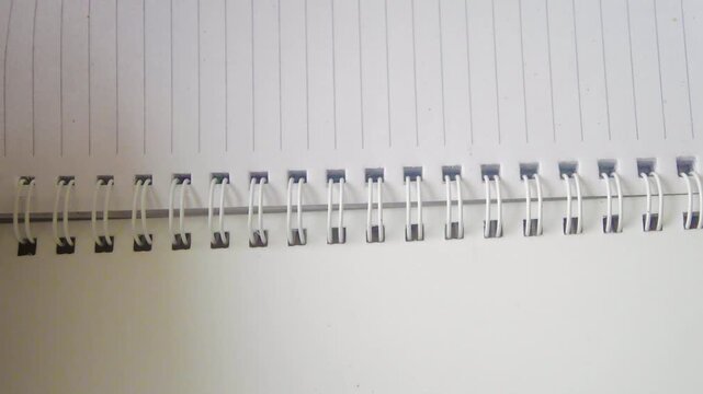 This video shows a close up view of a spiral notebook with lined pages, perfect for writing, note taking, or journaling. The notebook simple design makes it versatile for various uses.