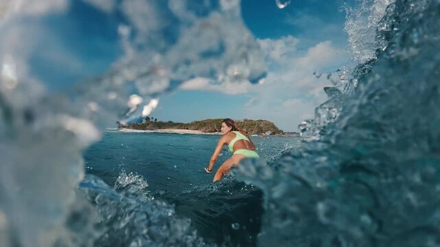 Woman surfer in bikini rides the ocean wave in the Maldives. In water and underwater view of the surfer on the wave