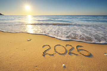 2026 text symbol of new year on the sea sand beach shore during sunset.