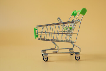An empty tiny shopping cart on color background.
