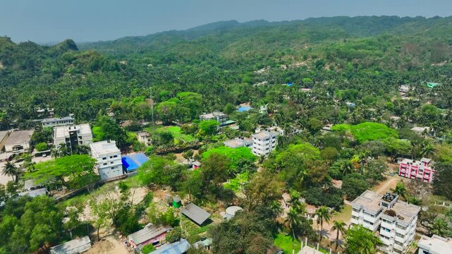 Aerial view of a densely vegetated coastal town nestled against lush green hills under a bright sky Teknaf, Cox's Bazar, Bangladesh